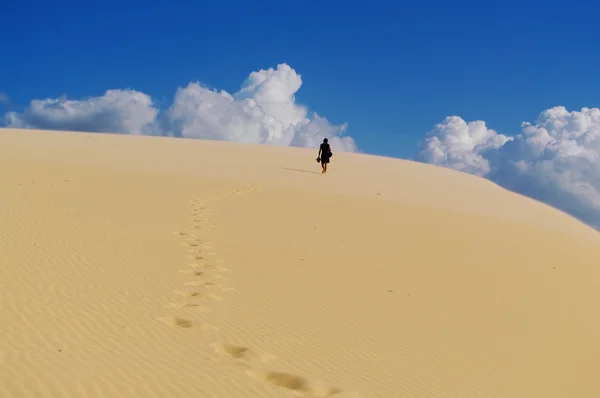 Человек ходит босиком по песчаной дюне — стоковое фото