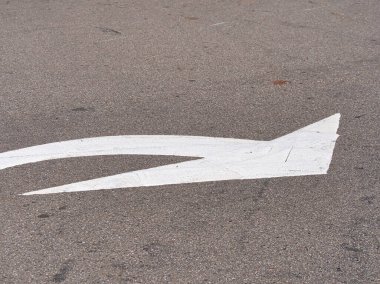 Kaba, yıpranmış asfalt kaldırıma çizilmiş beyaz bir ok, bir yönü ya da bir yol yüzeyinde faydalı ve işlevsel bir estetik ile dönmeyi gösterir..