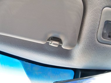 Bir aracın içinde gri bir araba güneşliği ve tavan lambası var. Mavi bir ön cam görünür. Sürücünün bakış açısından net bir görüş sağlıyor..