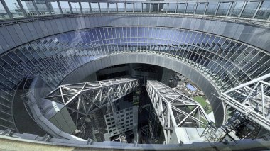 Japonya 'nın Osaka kentindeki modern cam gökdelenin açık merkezine bakan yüksek açılı bir manzara, tarafları birbirine bağlayan yapısal köprüler içeriyor..