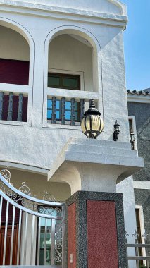 Beyaz kemerli bir kemer, detaylı bir aydınlatma armatürü ve dekoratif tasarımlı metal bir kapı içeren bir binanın girişinin yakından görüntüsü, hepsi Tayvan, Taipei 'de açık mavi bir gökyüzünün altında..