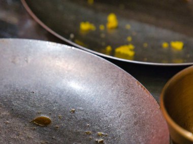 Kirli metal tencerelerin yakın plan görüntüsü, görünür sarı yemek artıkları ve bronz bir tencere..