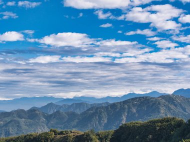 Yumuşak beyaz bulutlar berrak bir günde dingin bir dağ sırasının üzerinde sürüklenir, derin bir sükunet hissi uyandırır ve doğal dünyanın sonsuzluğunu.