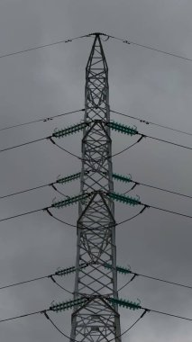 Bulutlu bir günde yalnız bir elektrik hattı, siyah beyaz bir fotoğraf.