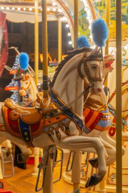 Gdansk, Polonya - 25 Kasım 2024 Atlıkarınca hareket halindeki sıcak bayram ışıklarıyla yakalandı. Geleneksel eğlence yolculuğu nostalji, aile eğlencesi ve şenlikli atmosferi çağrıştırıyor. Noel, çocukluk ve klasik fuar temaları için ideal.