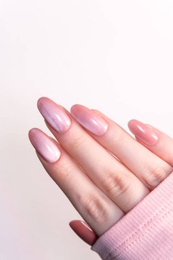 Manikür, güzellik tırnakları, zarif pembe badem şekilli parlak bir kaplama, kadınsı bir poz modern tırnak tasarımı, cilt bakımı ve güzellik konsepti..
