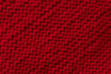 Kırmızı yün örgü desenli yakın çekim, detaylı örgü kumaş desenli görünür dikişler. Kış süveter kumaşı, sıcak el yapımı tekstil arka plan, moda giysi yüzeyi.