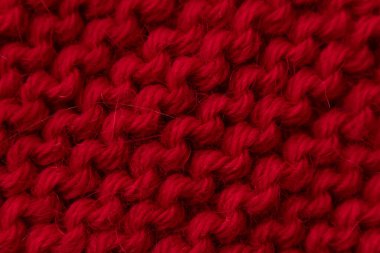 Kırmızı yün süveter dokusu, yakın çekim, yumuşak örgü deseni ve zengin lif detayı. Kış tekstil arka planı, rahat kumaş malzemesi, el yapımı el işi ve moda tasarımı konsepti.