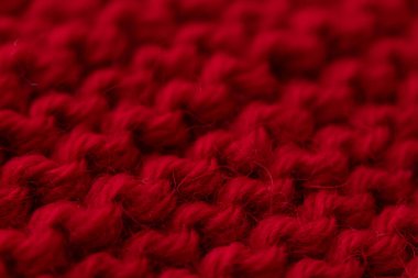 Kırmızı örülmüş makro kumaş, kabataslak dikişli soyut tekstil arkaplan. Sıcak kış kumaşı, el yapımı süveter, duvar kâğıdı veya tasarım için yumuşak yünlü malzeme..