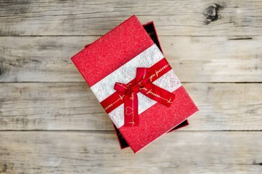 Eski ahşap arka planda fiyonklu kırmızı hediye kutusunu aç. Yukarıdan görüntüle