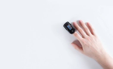 Beyaz arka planda işaret parmağında nabız oksimetresi var. Kan oksijeni ve nabız ölçümü. Yukarıdan bak. Boşluğu kopyala