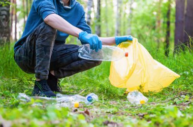 Doğada çöp toplama. Genç adam yaz ormanlarında plastik çöp topluyor.