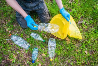 Doğada çöp toplama. Genç bir adam yaz ormanında plastik çöp topluyor. Yukarıdan görüntüle