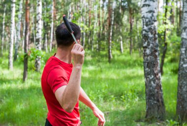 Bir adam, yaz ormanında bir hedefe bıçak fırlatıyor. Bıçak fırlatmak. 