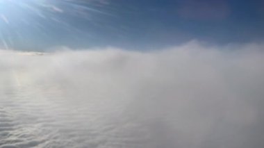 Sakin bir hava fotoğrafı bulutları ve açık gökyüzünü bir uçak penceresinden görüyor, uçuşun güzelliğini ve bulutların üzerindeki huzurlu atmosferi gösteriyor..
