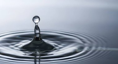 Durgun bir su yüzeyine çarpan bir su damlasının makro fotoğrafı güzel bir sıçrama ve eş merkezli dalgalanmalar yaratıyor. Görüntü serin, temiz ve minimalist bir estetiğe sahip..