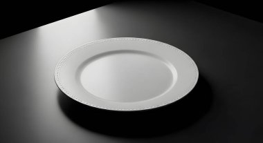 Basit bir beyaz levha, tek bir ışık kaynağıyla aydınlatılmış, koyu renkli bir yüzeyde oturur ve dramatik bir gölge yaratır..