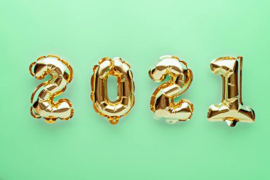 Yeşil zemin üzerinde 2021 numaralı altın folyo balonları, yeni yılın kompozisyonu, konsept