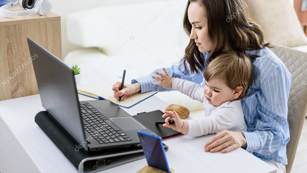 brunette woman with child sits at laptop making notes in notebook, online courses, remote work at home, Working from home concept