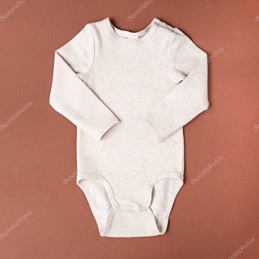 top view clean beige milk baby bodysuit on brown background, mock up, copy space