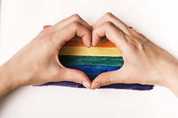 gay pride concept, hands with heart on lgbt flag, rainbow background, top view