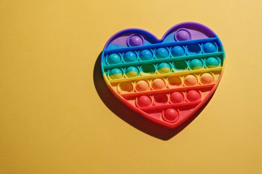 Sarı arka planda bir gökkuşağı patlat Kıpır kıpır oyuncak kopyala boşluk, moda anti-stres oyuncağı