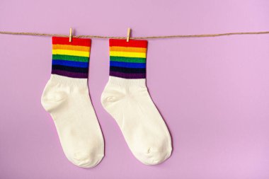 Pembe zemin üzerinde asılı renkli gökkuşağı çizgili beyaz çoraplar, lgbtq hediye fikri, kopyalama alanı, lgbt sembolü