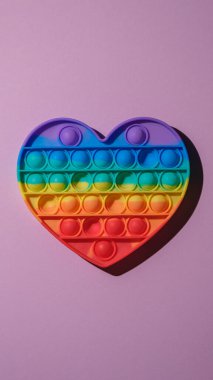 vertical image of pop it fidget toy on pink background, top view