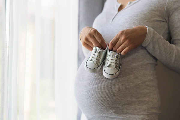 Donna Incinta Giacca Grigia Tiene Scarpe Bambini Mano Sulla Pancia — Foto Stock