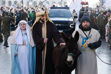 Varşova, Polonya - Ocak 06 2026: Mary ve Joseph gibi giyinmiş katılımcılar Üç Kralın Yürüyüşü sırasında bir eşekle yürüyorlar.