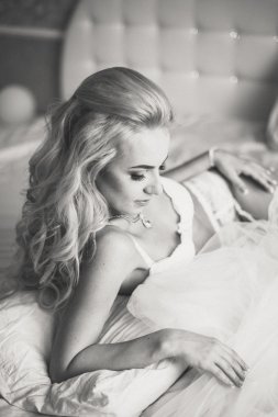 Güzel seksi genç kadın iç çamaşırı elinde bir örtü ile bir yatakta yatıyordu. Sabah gelin.