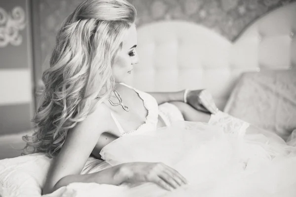 Szép szexi fiatal női fehérnemű feküdt egy ágyon a kezében fátyol. Reggel a menyasszony. — Stock Fotó