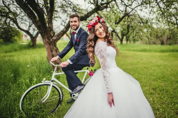 Жених и невеста позируют рядом с велосипедом — стоковое фото