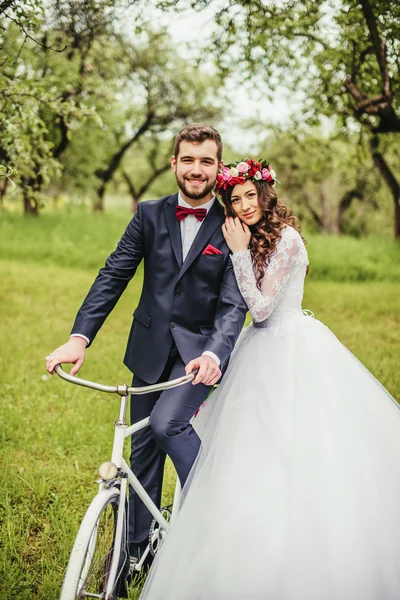 Жених и невеста позируют рядом с велосипедом — стоковое фото