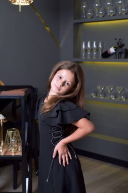 Modern iç mimariye sahip siyah elbiseli bir kızın portresi.
