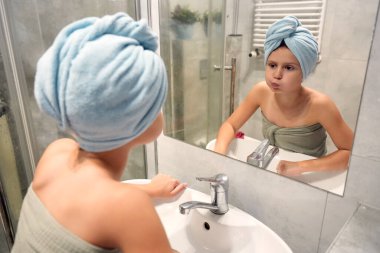 Modern banyo içlerindeki lavaboda başı havluyla yıkanmış bir çocuk.