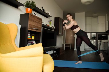 Lastik bantlar ve genişletici ile evde fitness, evde sağlık egzersizleri yapan genç kadın, Covid 2019 pandemik karantina sırasında eğitim