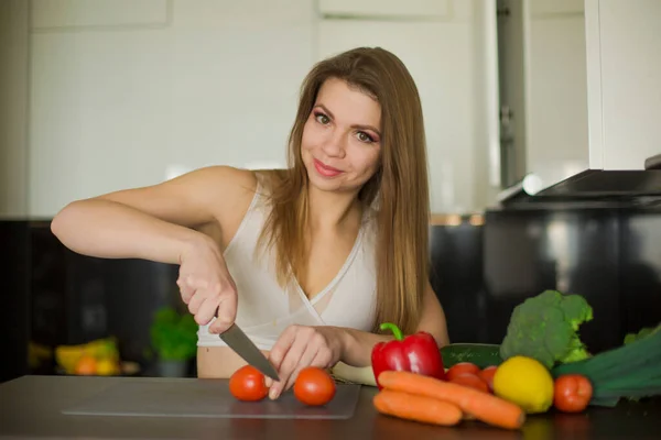 Genç sporcu kadın mutfakta duruyor, sağlıklı bir yemek hazırlıyor, sebze karışımı.