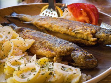 Lezzetli kızarmış balık, taze domates ve baharatlı patates.