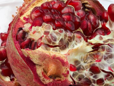 Taze bir nar, zengin, kırmızı tohumlarını ve karmaşık iç yapısını sergileyerek ikiye bölünür. Parlak renk ve eşsiz doku onun doğal güzelliğini ve tazeliğini vurgular.
