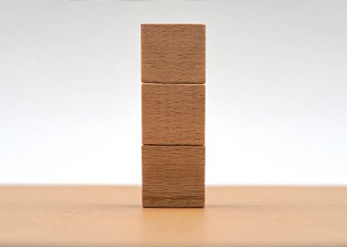 Üç tahta bloktan oluşan bir set düz bir yüzeye dikey olarak yerleştirilir. Bloklar eşit istiflenmiş, basit ve minimalist bir tasarım sergiliyorlar.