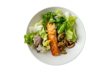 Somon filetosu taze salata yeşillikleri ve sotelenmiş mantarlarla birlikte beyaz bir tabağa konur. Bu tabak öğle yemeği için hazır.