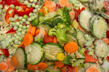 Bezelye, dilimlenmiş havuç, brokoli çiçeği ve kabak da dahil olmak üzere donmuş karışık sebzelerin yakın plan çekimi, yemek hazırlığı, yemek pişirme, sağlıklı yeme ve uygun donmuş gıda tarifleri.