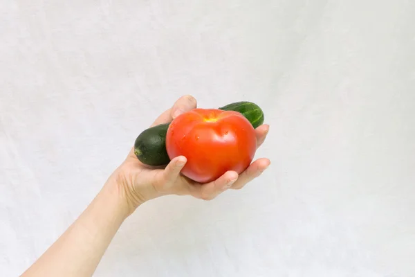 En su mano hay un tomate y un pepino — Foto de Stock