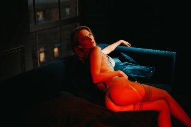 Mavi iç çamaşırlarıyla poz veren seksi sarışın kadın.