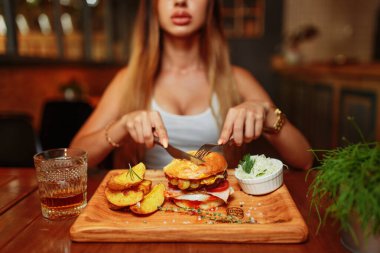 Lokantada lezzetli ızgara sulu burger yiyen seksi kadın. 