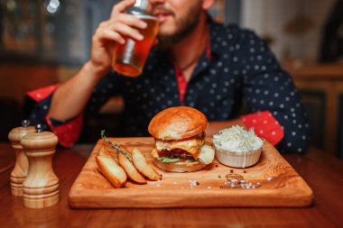 Bir tabak lezzetli yemeği olan bir adam, patates kızartmalı burger, yakın çekim.