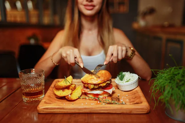 レストランでおいしい焼きジューシーなバーガーを食べるセクシーな女性 — ストック写真