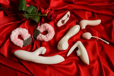 Kırmızı örtüde kelepçeler, bir gül ve bir sürü farklı seks oyuncakları var..