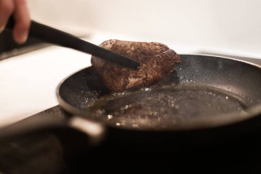 Biberiyeli ve tereyağlı tavada biftek pişirme süreci.